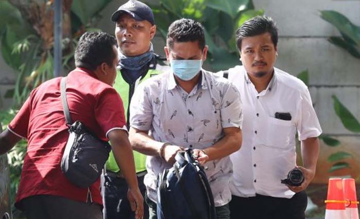 Kepala Kantor Imigrasi Klas I Mataram, NTB, Kueniadie (memakai masker) dengan dikawal  petugas tiba di gedung KPK, Jakarta, Selasa kemarin. (Foto:JawaPos)
