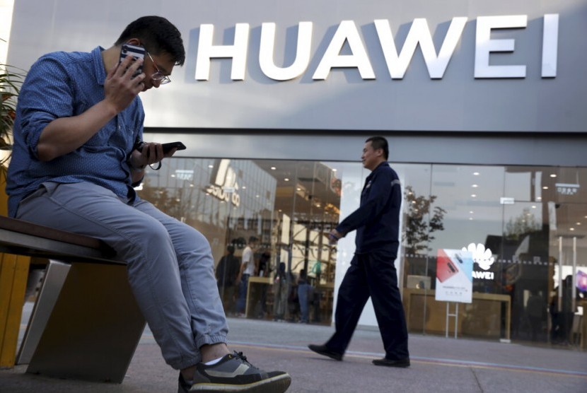Seorang pria menggunakan ponselnya di depan toko Huawei di Beijing, Cina. (Foto: AP)