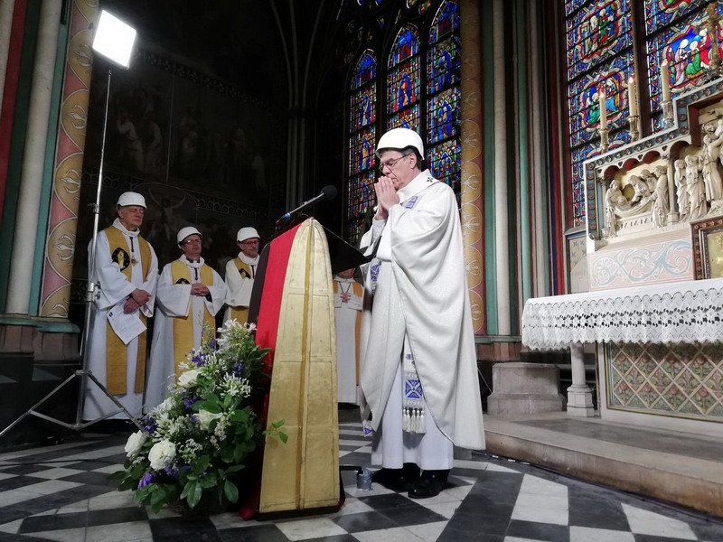 Pemimpin jemaat mengenakan helm selama memimpin misa di Katedral Notre Dame.