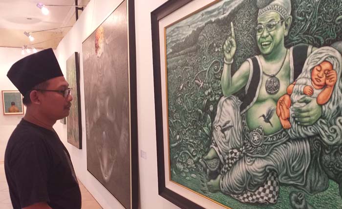 A.Anzieb, koordinator sekaligus kurator Pameran Rakornas 3 Lesbumi NU, memperhatikan salah satu lukisan yang dipamerkan. (Foto:Anis)