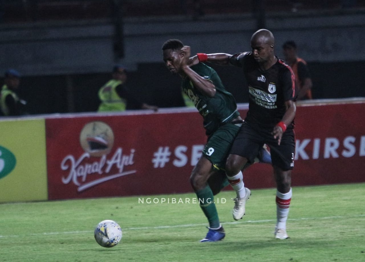 Striker Persebaya, Amido Balde, harus bekerja keras untuk melepaskan kawalan pemain belakang Persipura, Andre Ribeiro dos Santos. (Foto: Haris/ngopibareng.id)