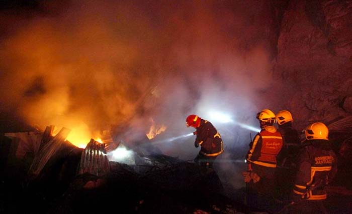 Petugas pemadam kebakaran sedang memadamkan api yang menghabiskan rumah di Sawah Besar, Minggu malam. (Foto:Antara)