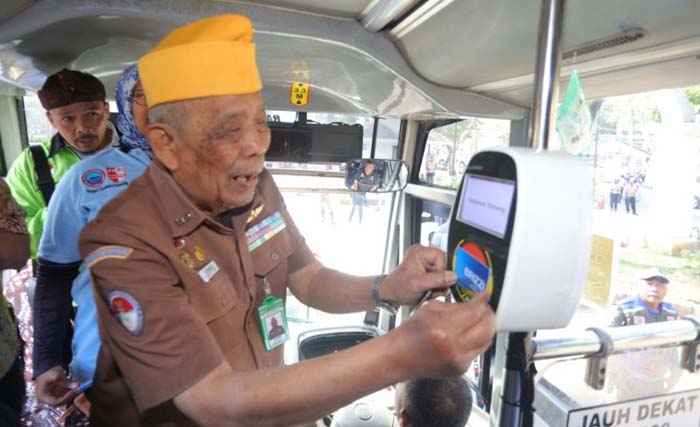 Seorang anggota veteran membayar dengane-money saat naik bus Trans Metro Bandung. (Foto:WartaKini)