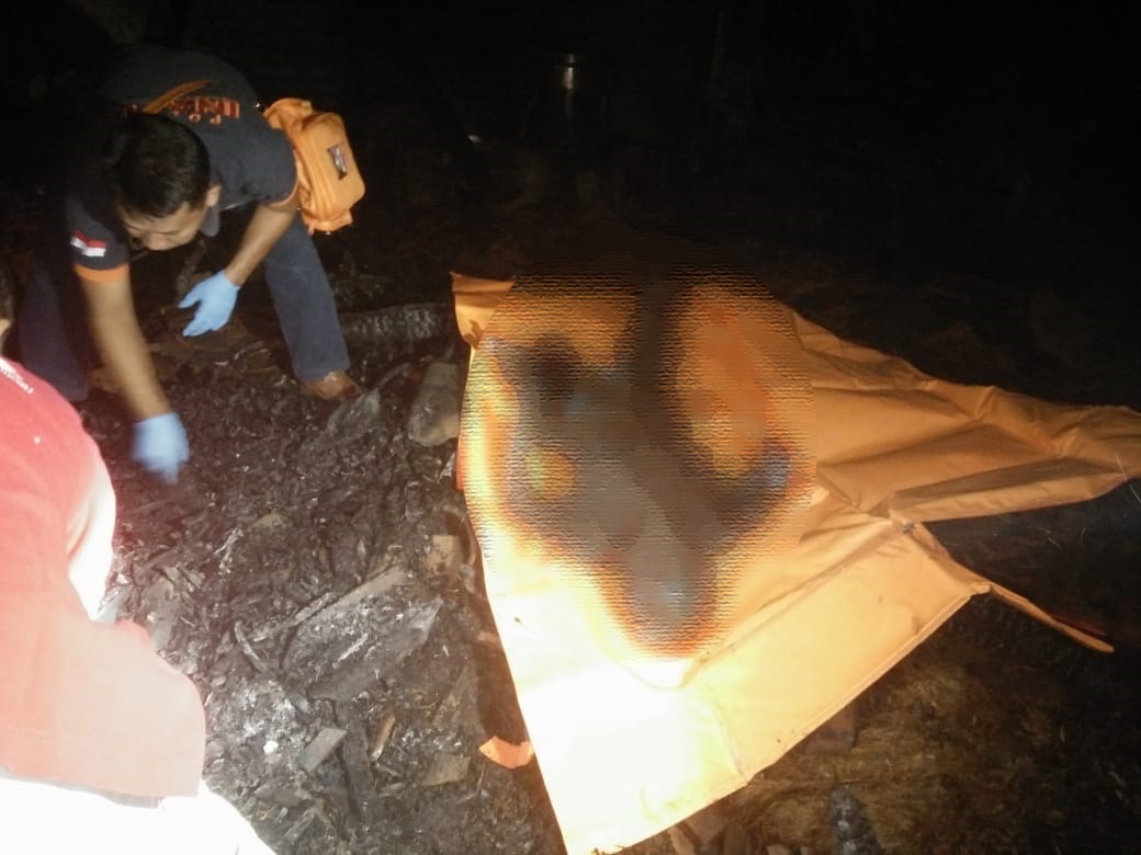 Petugas dari Polsek Plemahan Kediri saat memeriksa jasad korban yang hangus terbakar. (Foto: Fendi/ngopibareng.id) 