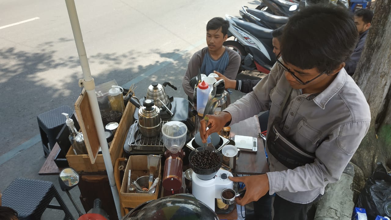 Achmad Yusuf ketika meracik kopi di atas gerobak modifikasinya. (Foto: Fendi/ngopibareng.id)