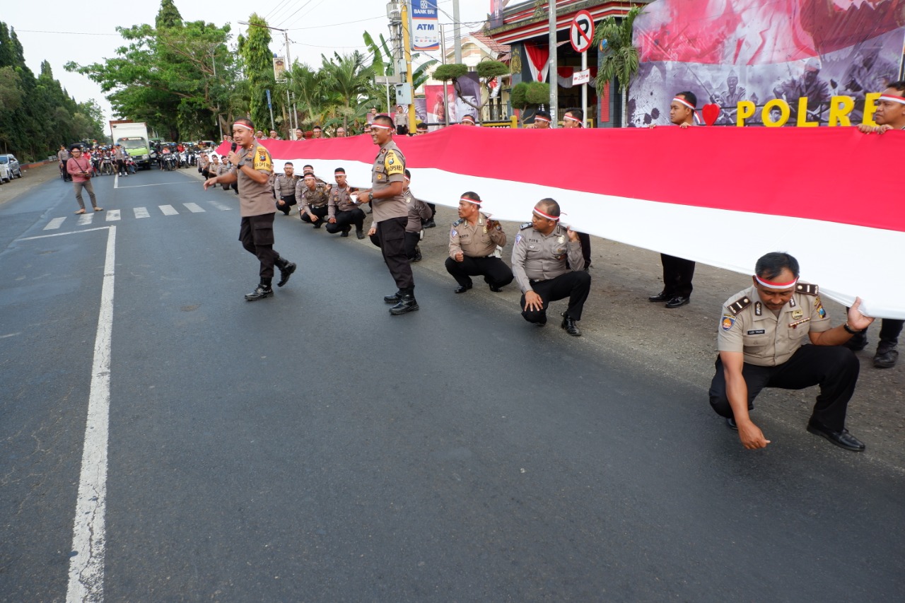 Sejumlah aparat kepolisian Polres Probolinggo membentangkan bendera merah putih sepanjang 100 meter, Jumat, 16 Agustus 2019. (Foto: Iksan/ngopibareng.id)