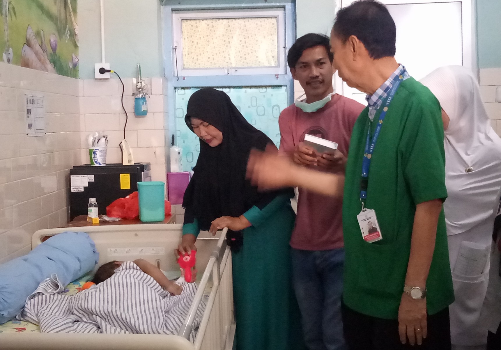 Ketua Tim Pusat Pelayanan Kembar Siam Terpadu RSUD Dr. Soetomo Surabaya dr. Agus Harianto berbincang dengan ayah bayi kembar siam, Yayasrin di kamar rawat inap anak Bobo RSUD Dr. Soetomo.  (Foto: Pita/ngopibareng.id) 