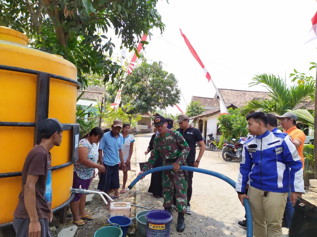 Babinsa Koramil 0815/08 Dawarblandong Serka M. Irfan saat membantu droping air bersih di Dusun Tempuran Desa Simongagrok