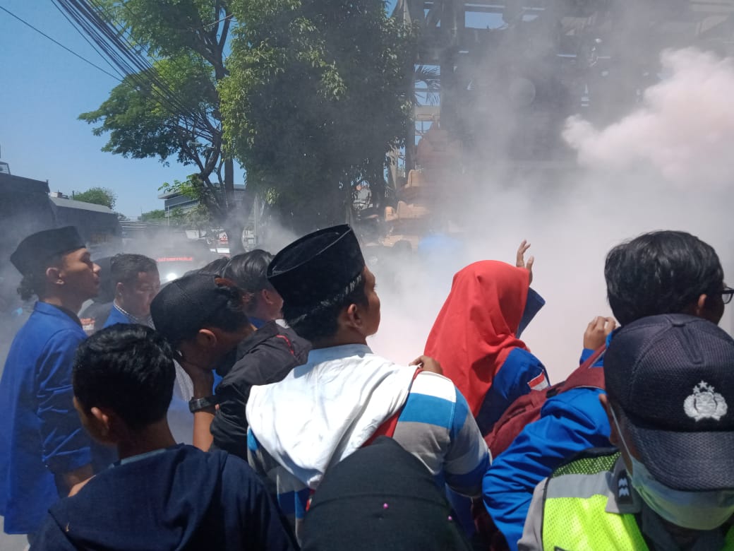 Polisi saat memadamkan api dan terkena mahasiswa yang demo. (Foto: Alief/ngopibareng.id)