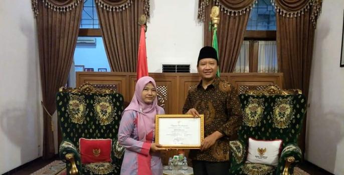 Ummi Kulsum saat foto bersama Bupati Pasuruan Irsyad Yusuf bersama penghargaan sebagai Juara Nasional Tutor Keaksaraan. (Foto: Dok Humas)