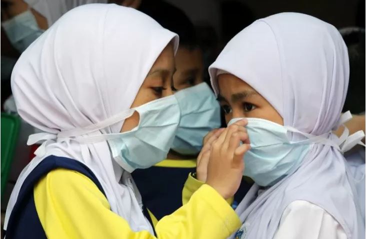Dua siswa menutupi wajah mereka dengan masker di sebuah sekolah saat kabut asap menyelimuti Kuala Lumpur, Malaysia, Jumat 13 September 2019. (Foto: Reuters/Lim  Huey Teng) 