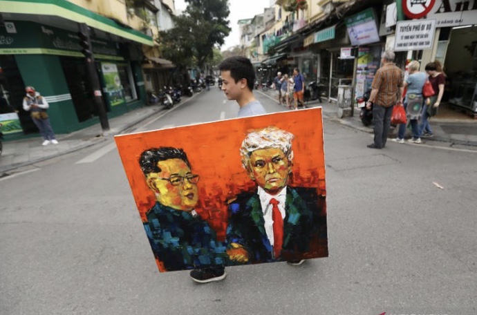 Seorang pria membawa lukisan pemimpin Korea Utara Kim Jong Un dan Presiden Amerika Serikat Donald Trump menjelang ktt Korut-AS di Hanoi, Vietnam. (Foto: Antara/Reuters)