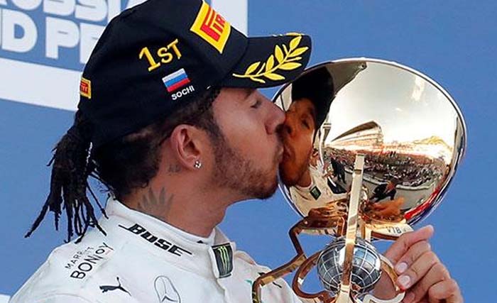 Lewis Hamilton mencium tropinya usai memenangi Grand Prix Rusia, Minggu malam WIB). (Foto: AFP)