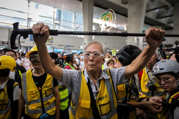 Kakek Wong (85) mengangkat tongkatnya. Dia merupakan anggota dari relawan bernama Protect the Children yang berdiri di antara demonstran dan polisi Hong Kong, dengan harapan bisa meredakan ketegangan. (Foto: AFP)