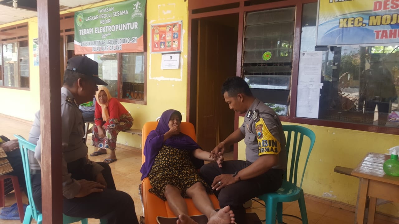 Anggota babinkamtibmas Polsek Mojo, Bripka Agus Budiono, mengobati orang sakit. (Foto: Fendhy Plesmana/ngopibareng.id) 