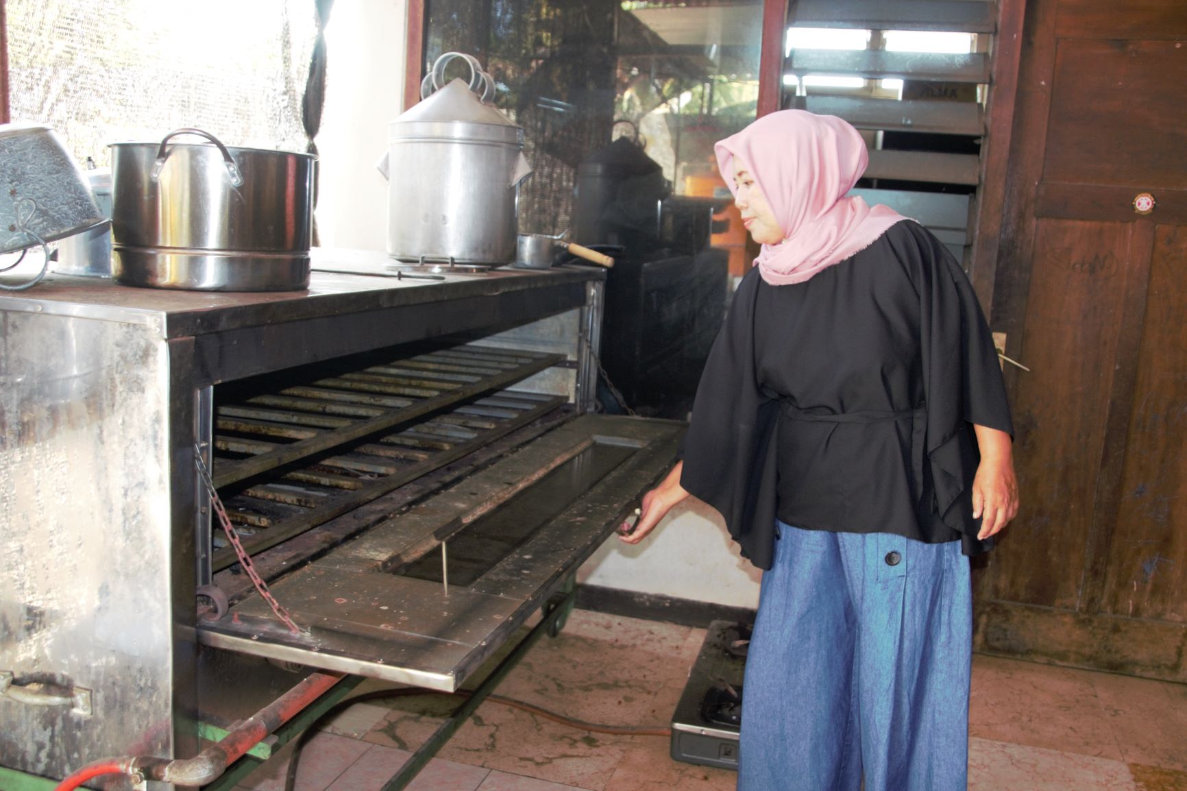 Esti Wahyuni saat menunjukkan oven pembuat rotinya yang terletak di rumah produksinya yang terletak di Jalan KH Usman 10, Kota Mojokerto. (Foto: Rizal/ngopibareng.id)  