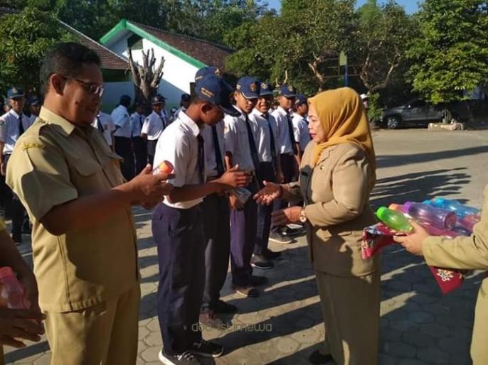 Kepala Sekolah SMPN 2 Bangil, Tanti Rahayu sedang membagikan botol minuman (tumbler) khusus kepada para siswanya. Aktivitas ini bertujuan mengurangi sampah plastik. (Foto: Dok Humas)