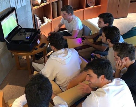 Pembalap Max Verstappen, Nico Hulkenberg, dan Carlos Sainz bermain PlayStation game FIFA di kamar hotel.