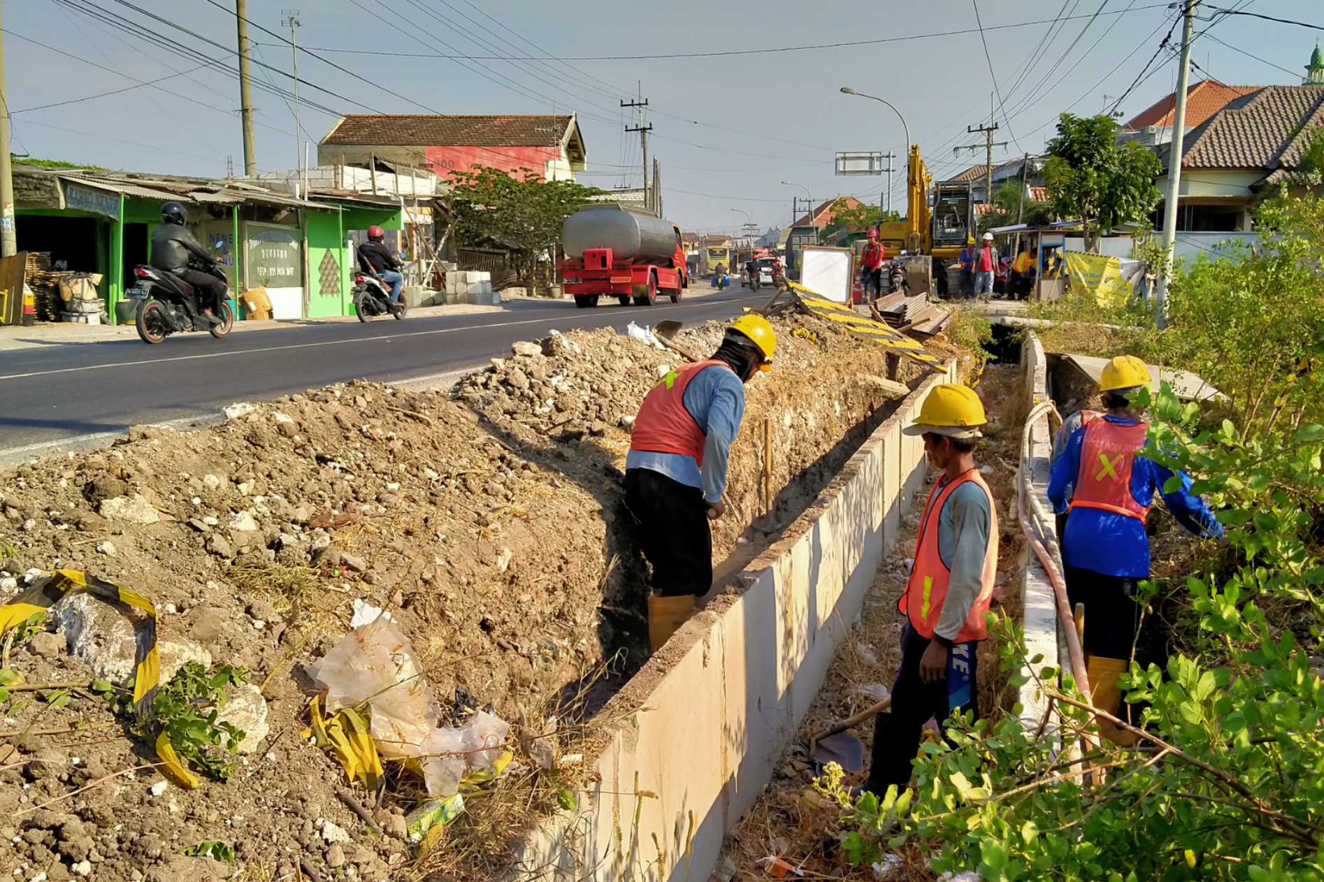 Para pekerja proyek pemasangan pipa utama gas PGN sedang membersihkan jalur yang akan digunakan pipa di Jalan Raya Semabayat, Gresik, Selasa (15/10/2019). (Fariz/ngopibareng.id)