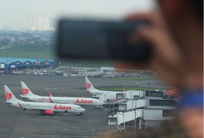  Pekerja memotret sejumlah pesawat Boeing seri 737-800 dan 737-900ER milik Lion Air yang terparkir di Terminal 1 A Bandara Soekarno Hatta, Tangerang, Banten, Jumat 15 Maret 2019. (Foto: Antara/Muhammad Iqbal)