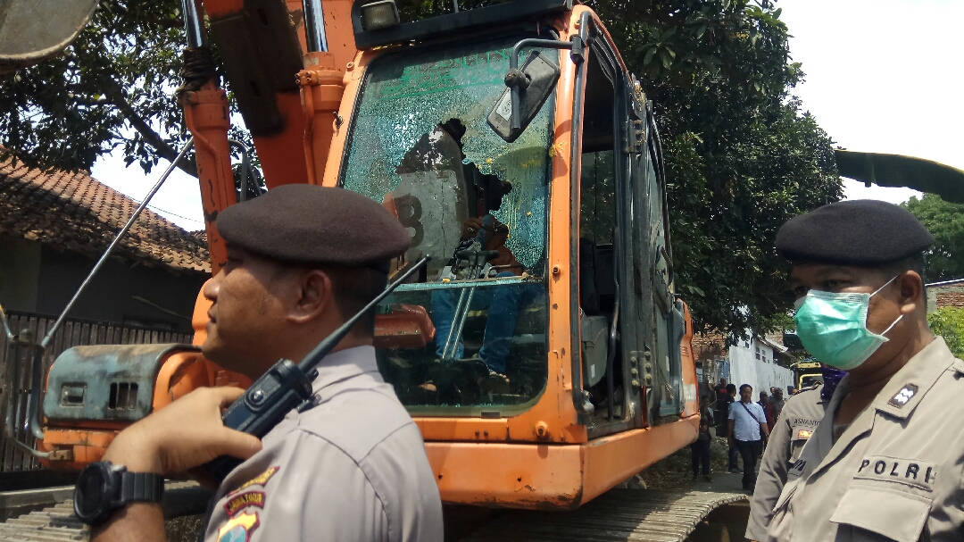 Petugas mengamankan alat berat yang rusak setelah dilempari massa yang menolak eksekusi