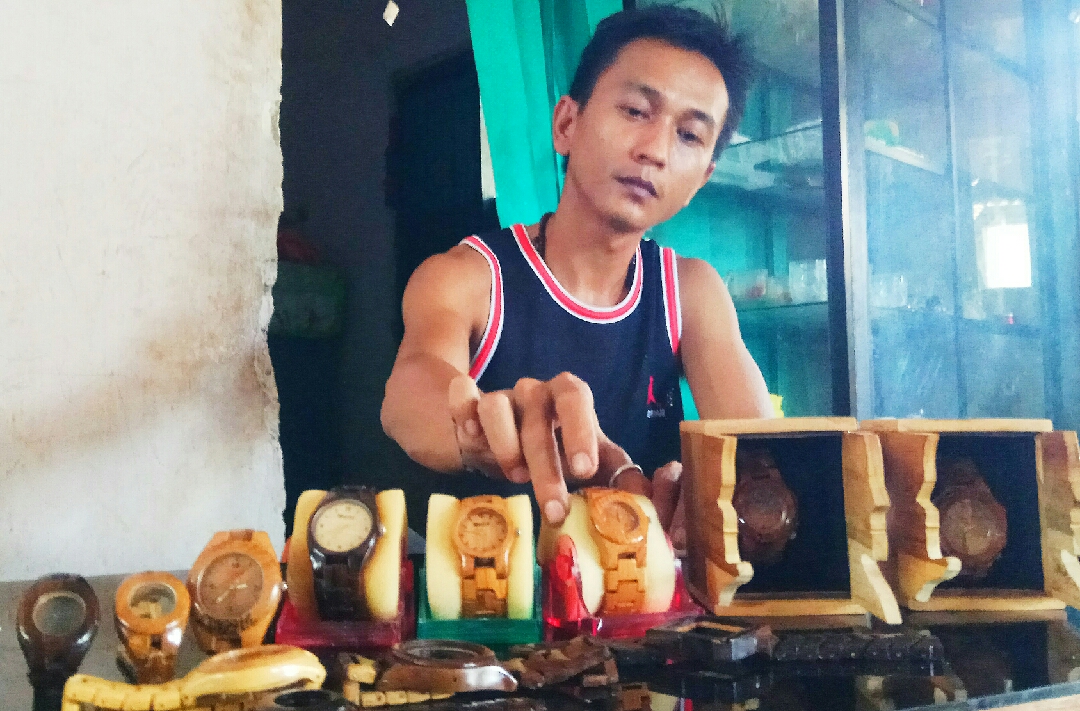 Andi Akbar menunjukkan beberapa jam tangan berbahan kayu hasil karyanya. (Foto: Hujaini/ngopibareng.id)