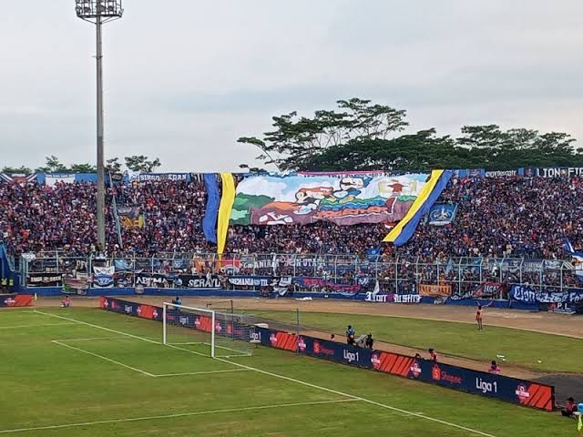 Spanduk yang menggambarkan kemesraan antara Aremania dan Jakmania di Stadion Kanjuruhan, Malang. (Foto: Theo/Ngopibareng.id)