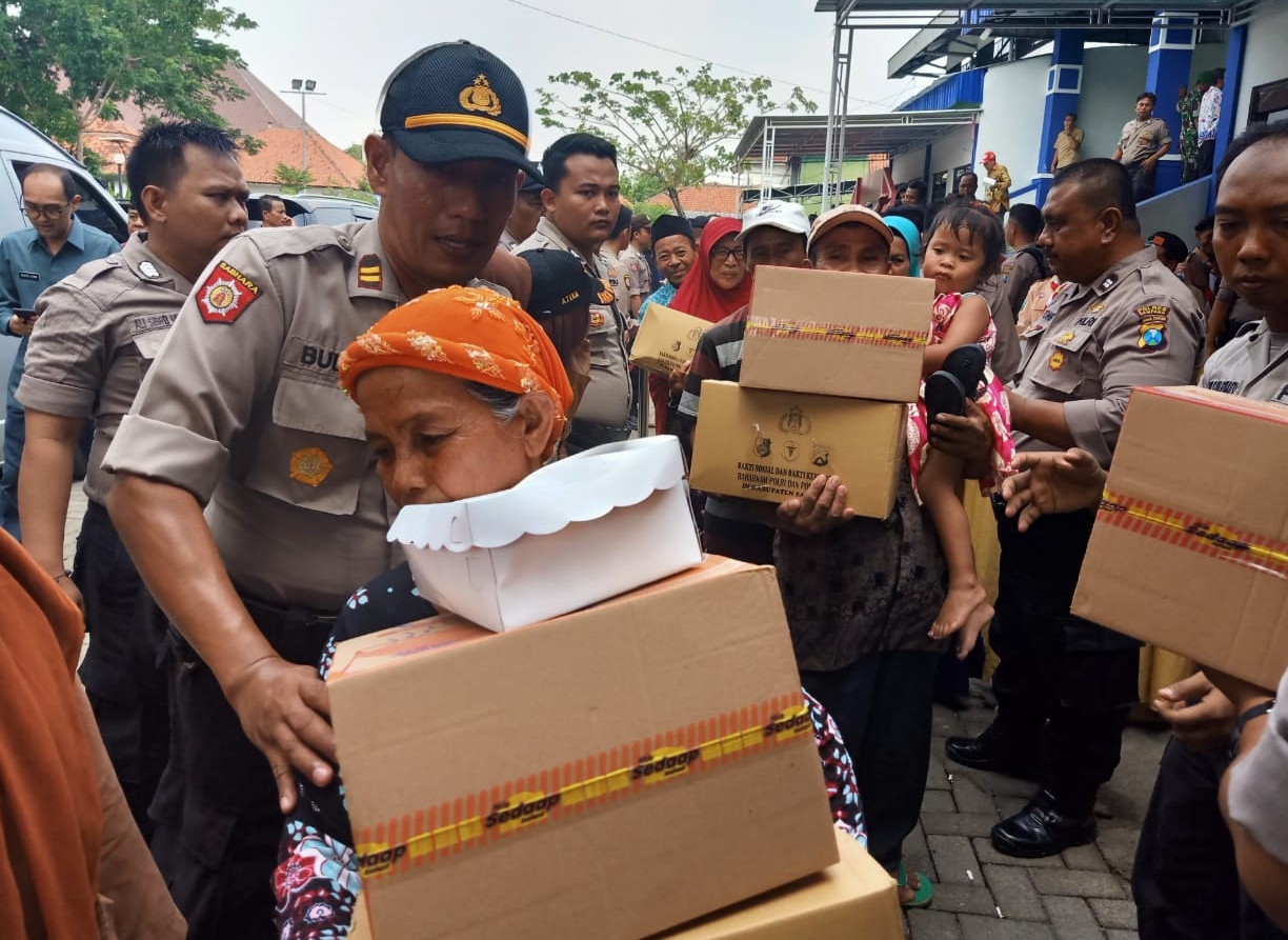 Sejumlah aparat kepolisian membagi bantuan kepada masyarakat di GOR Wijaya Kusuma, Sampang, Jumat 13 Desember 2019. (Foto: Istimewa)