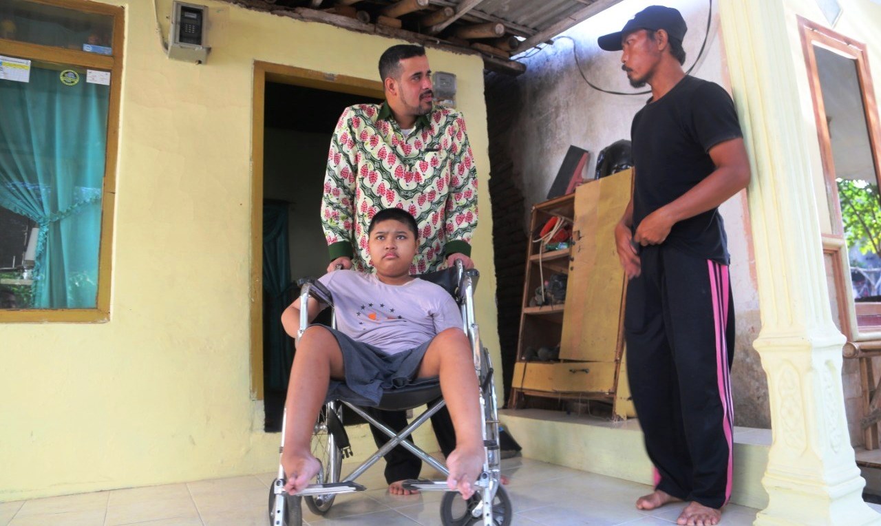  Wali Kota Probolinggo, Hadi Zainal Abidin mendorong kursi roda yang dinaiki Febri Dwi Saputra, bocah yang empat tahun lumpuh. (Foto: Humas Pemkot) 