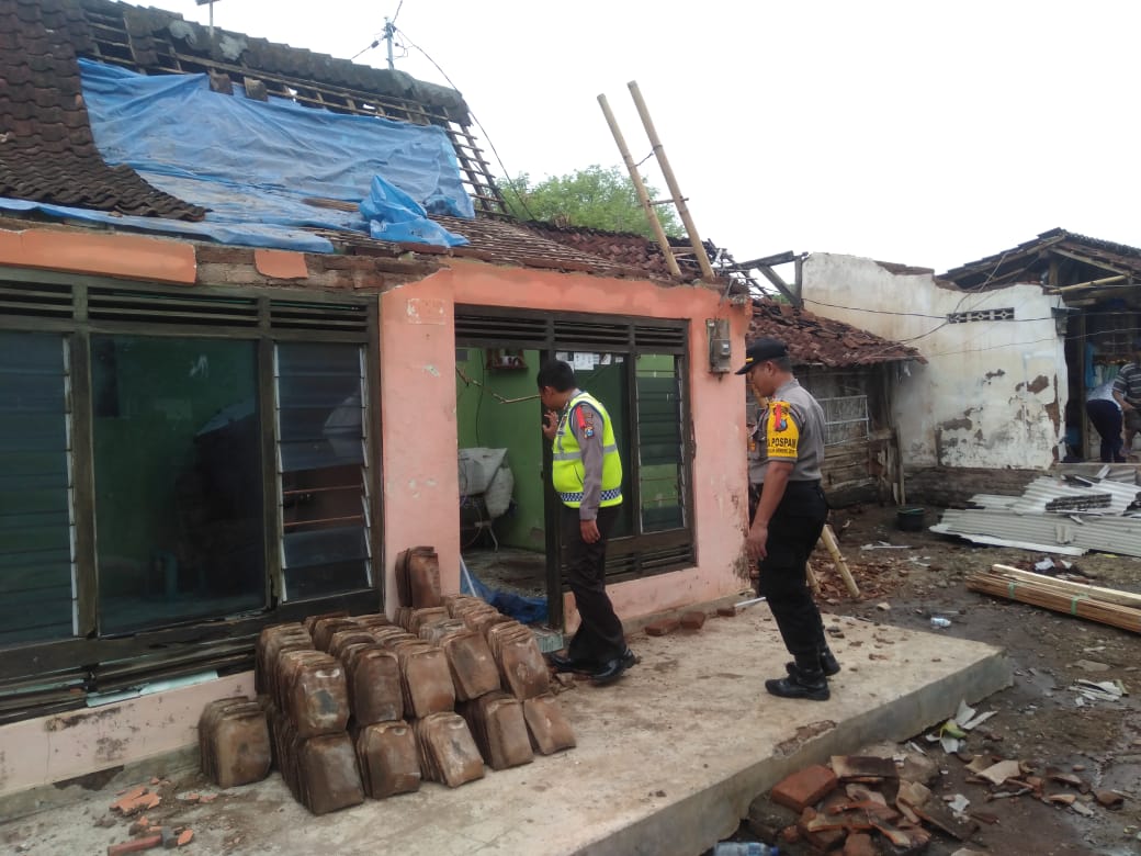 Petugas Polsek Wongsorejo mengecek rumah warga yang mengalami kerusakan akibat diterjang angin puting beliung (Foto: Polsek Wongsorejo)