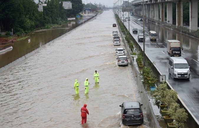 Petugas mengatur kendaraan yang melintasi air yang menggenangi Jalan Tol Cikampek di sekitar Jati Bening, Bekasi, Rabu 01 Januari 2020, setelah hujan lebat semalaman mengguyur Jakarta, Depok, Tangerang, dan Bekasi. (Foto: Antara/Saptono)