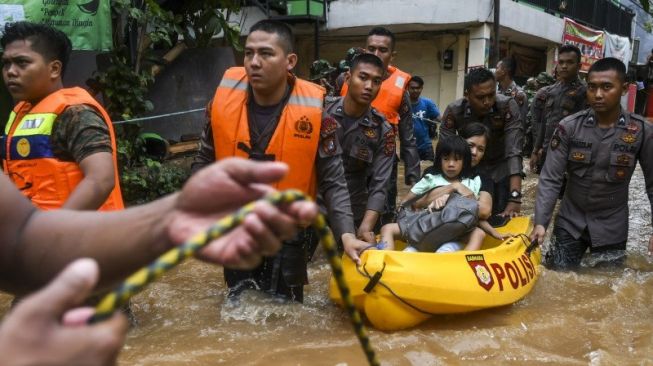  Personel Kepolisian dan TNI mengevakuasi warga yang terjebak banjir di kawasan Cipinang Melayu, Jakarta, Rabu 1 Januari 2020. Foto: Antara/Galih Pradipta)