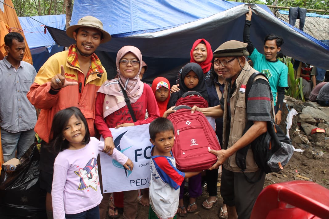 Wartawan Ngopibareng.id Asmanu Sudarso mewakili Forum Wartawan Pendidikan menyerahkan bantuan secara simbolis berupa tas, alat tulis dan seragam sekolah di Desa Bungur Mekar, Lebak, Banten, Sabtu 11 Januari 2020. (Foto: Fortadik)