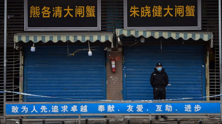 Petugas dengan masker sedang menjaga pertokoan di Wuhan setelah terjangkit wabah virus. (By Disway)