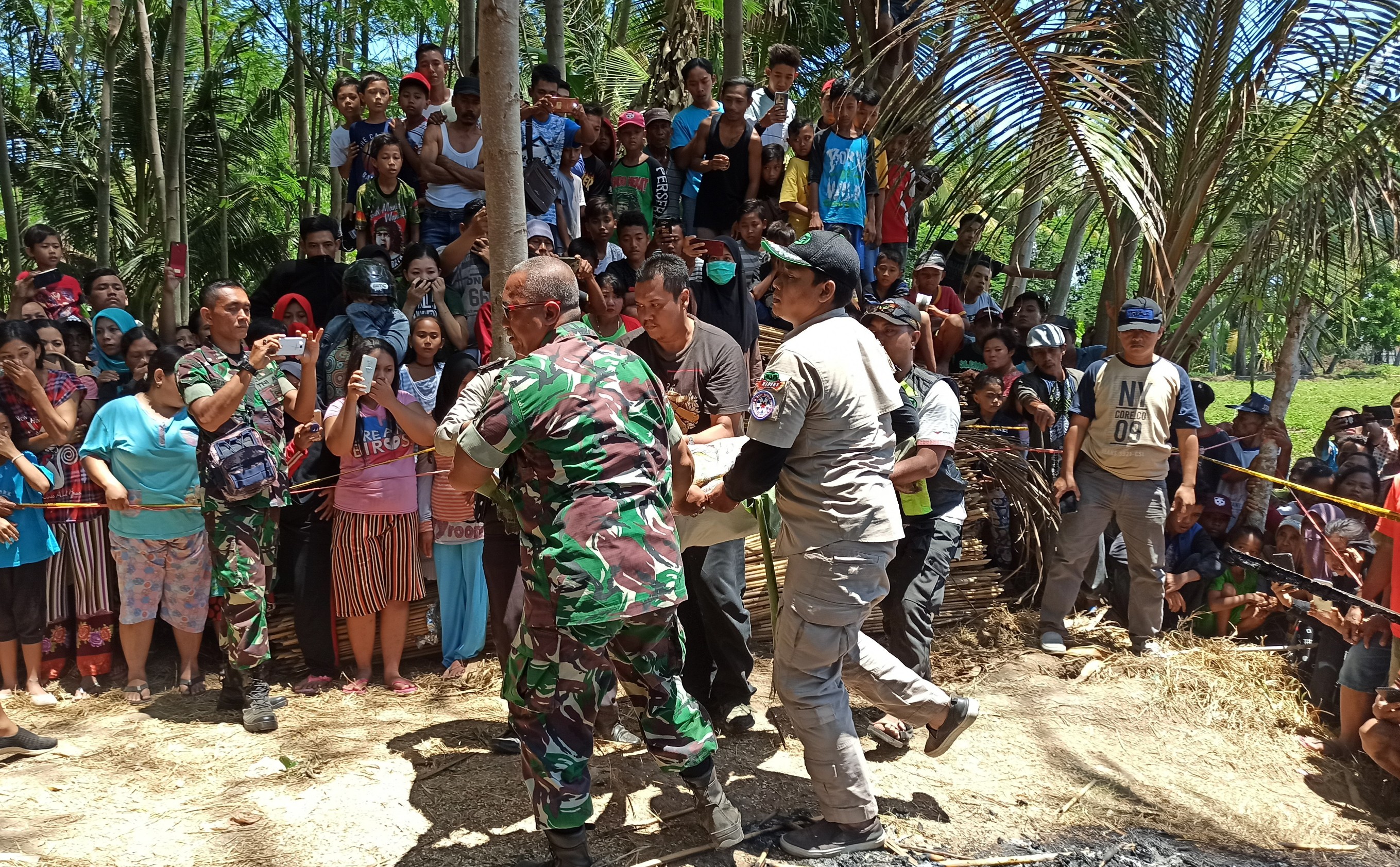 Petugas mengevakuasi mayat perempuan yang ditemukan dalam keadaan hangus terbakar. (Foto: Hujaini/ngopibareng.id)