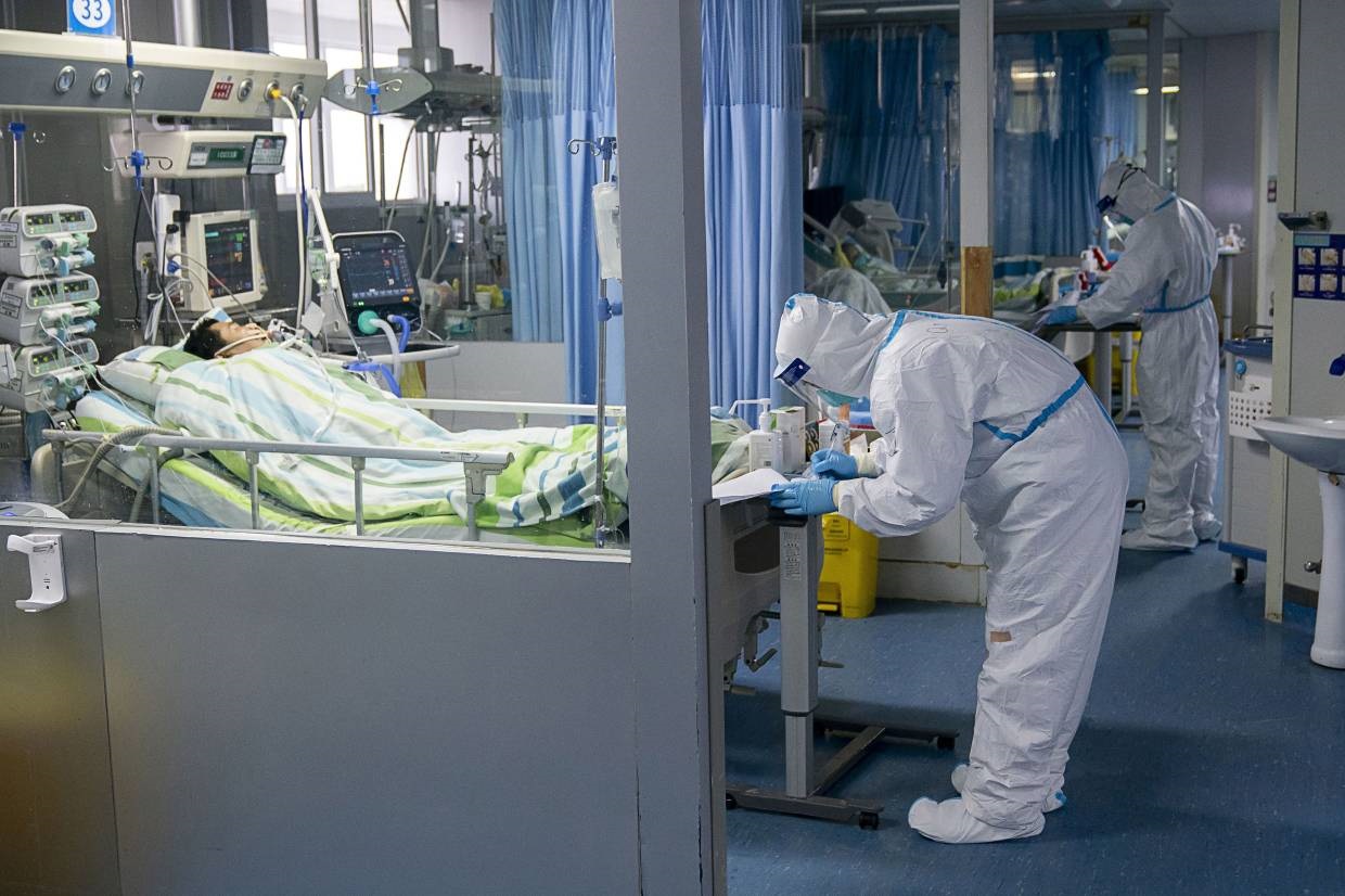Beberapa pekerja medis sedang menangani salah seorang WNA yang terinfeksi virus Corona di China. (Foto: People's Daily)