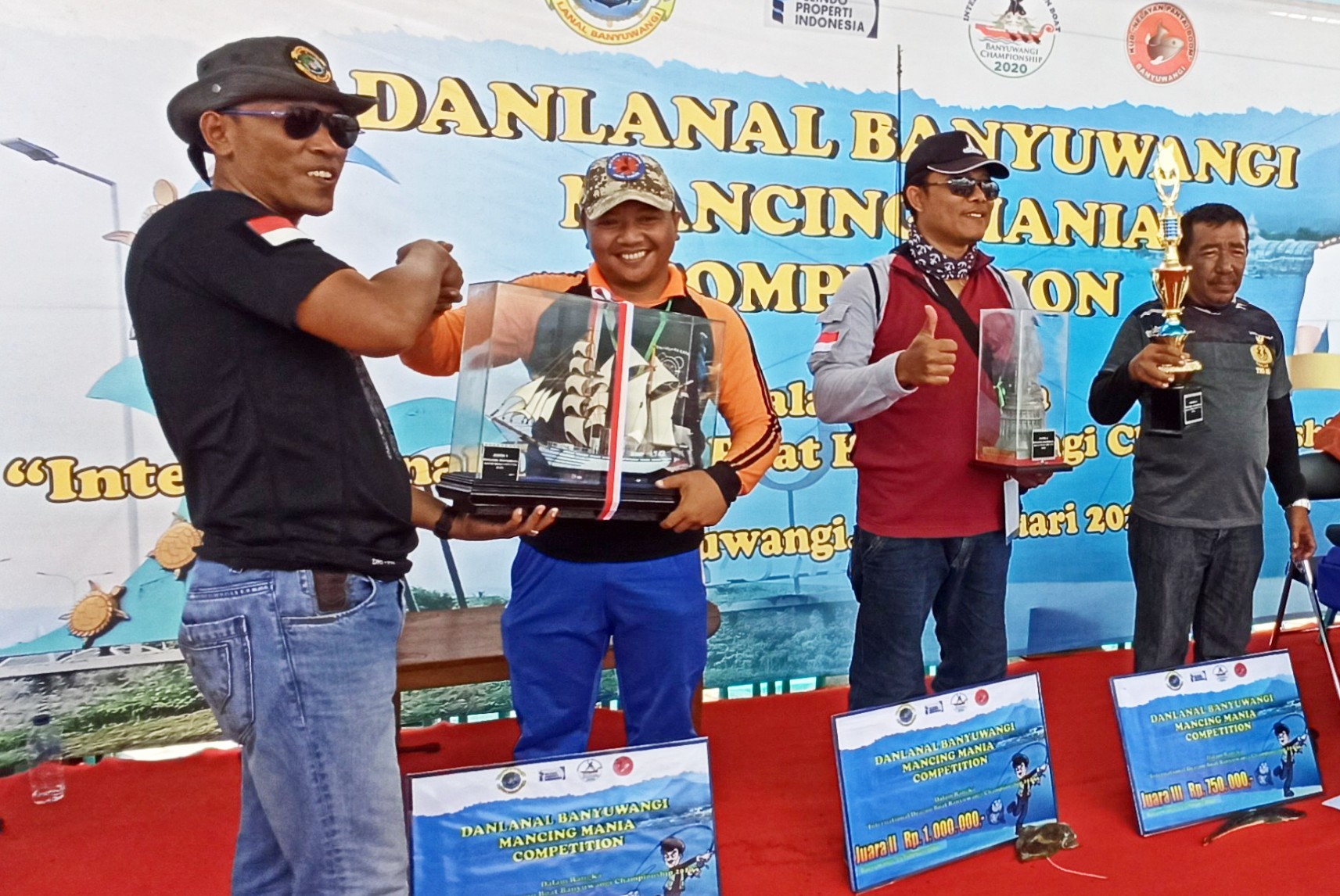 Komandan Lanal Banyuwangi Letkol Laut (P) Yulius Azz Zaenal menyerahkan trophy pada pemenang lomba memancing (foto : Hujaini/ngopinareng.id)