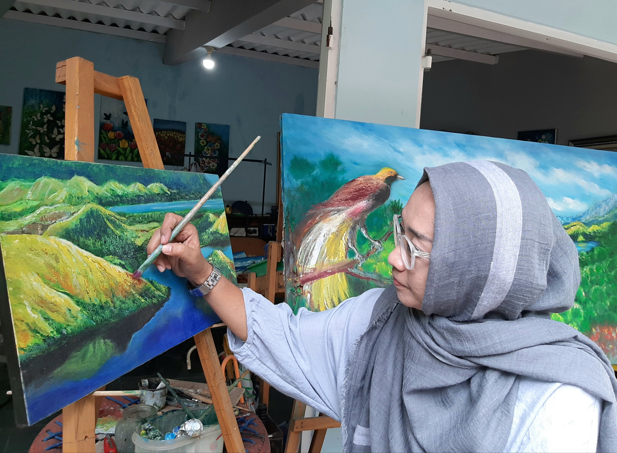 Ovy saat melukis Danau Sentani yang menjadi ikon Papua. (Foto: Pita Sari/Ngopibareng.id)