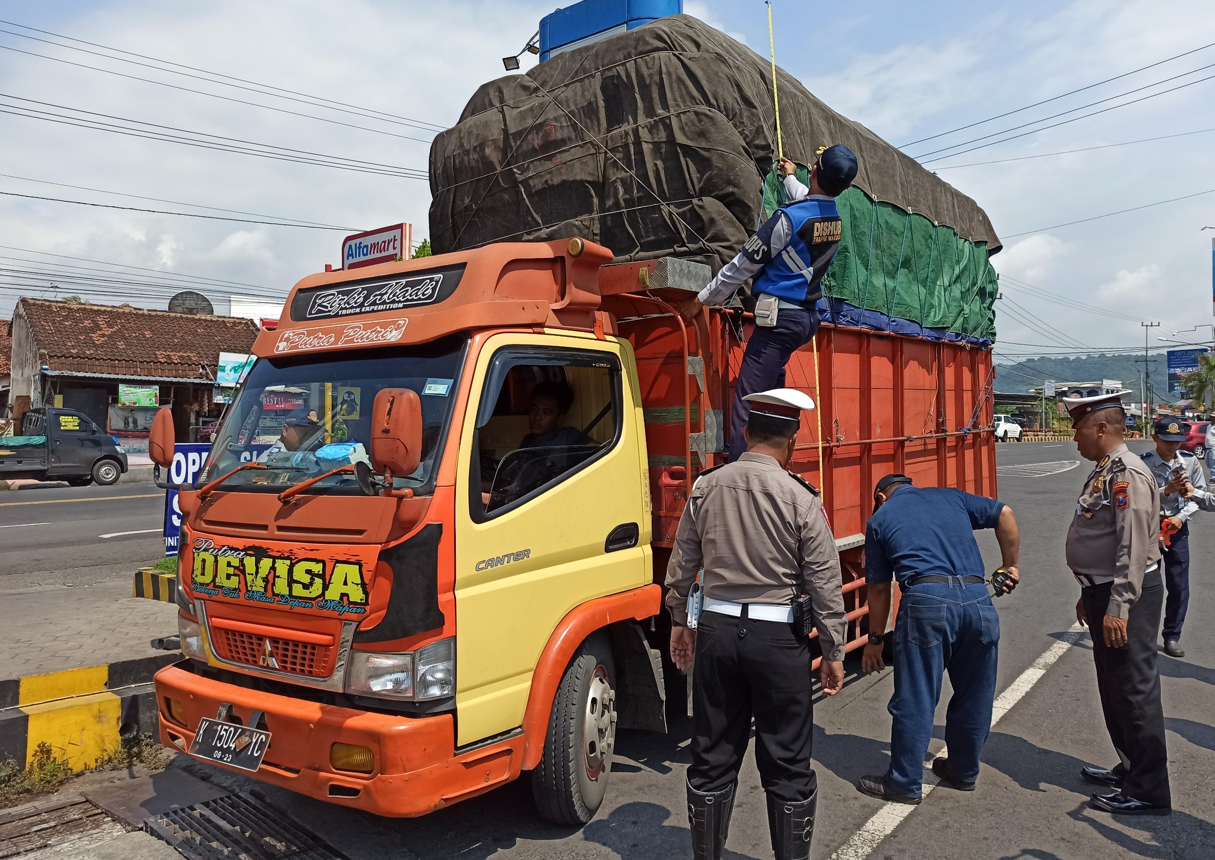 Petugas gabungan sedang mengecek dimensi dan muatan sebuah truk di depan pintu masuk pelabuhan penyeberangan Ketapang, Banyuwangi. (Foto: Muh Hujaini/Ngopibareng.id)