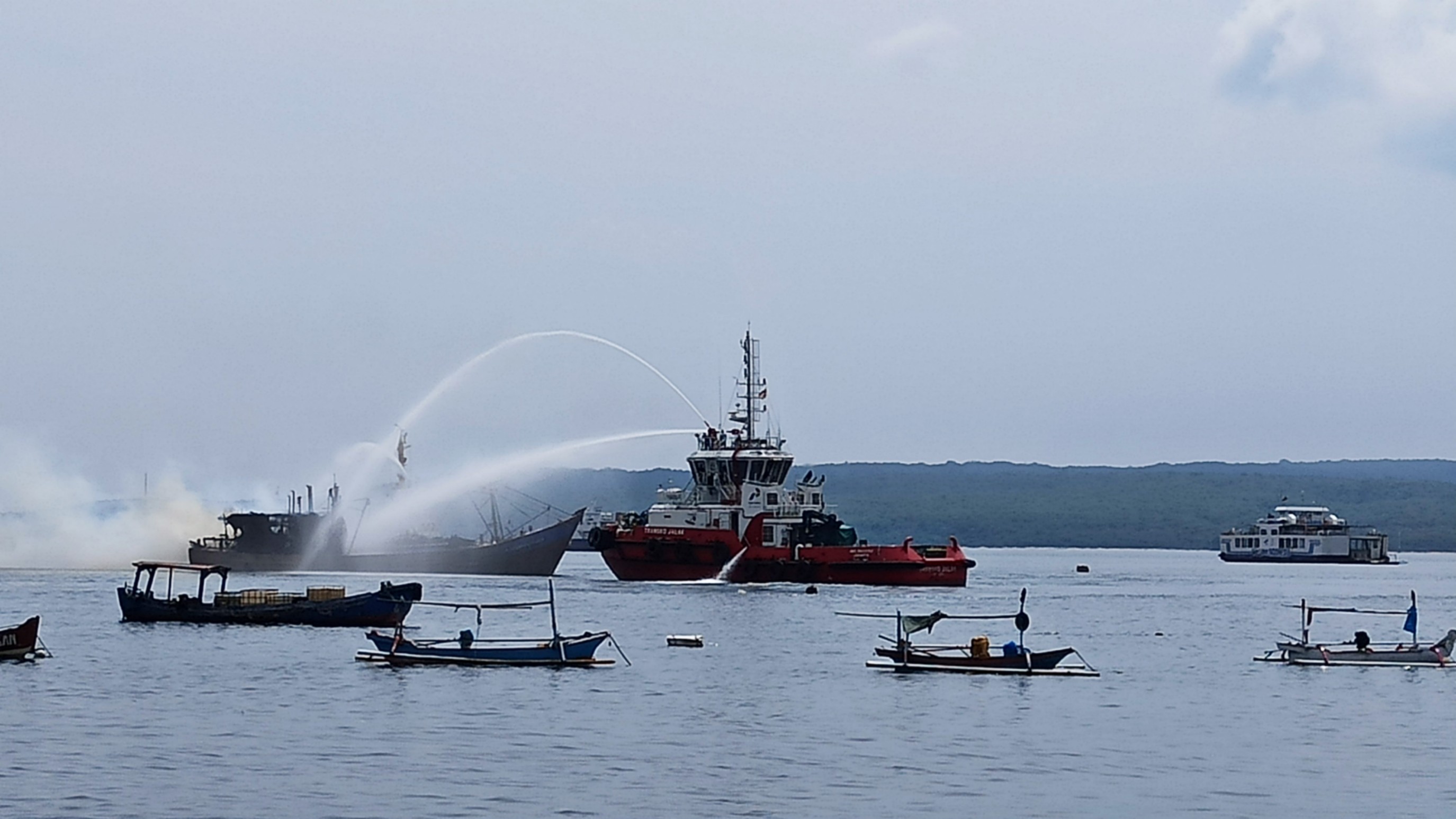 Kapal pemadam mencoba memadamkan api yang membakar KM Victori Utama (Foto: Hujaini/Ngopibareng.id)