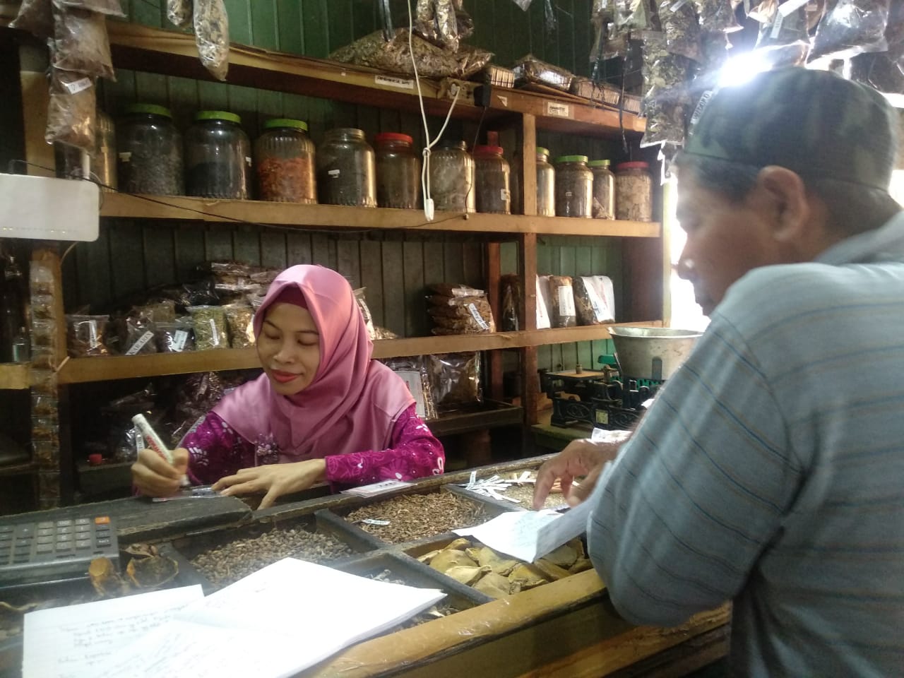 Wanti, pemilik warung Jamu Tradisional Ibu Hadi, saat melayani pembeli di pasar Genteng, Surabaya. (Foto: Rizqi Mutqiyyah/Ngopibareng.id)