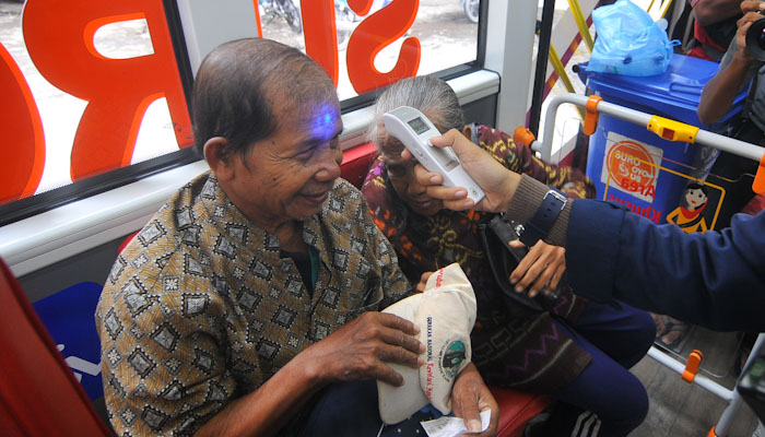 Sepasang kakek dan nenek dicek suhu tubuhnya oleh seorang petugas dari Dishub Surabaya. (Foto: Erfan Hazransyah/Ngopibareng.id)