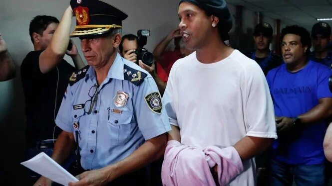 Digiring polisi, Ronaldinho dengan tangan diborgol menjalani persidangan. (Foto: Thesun)  