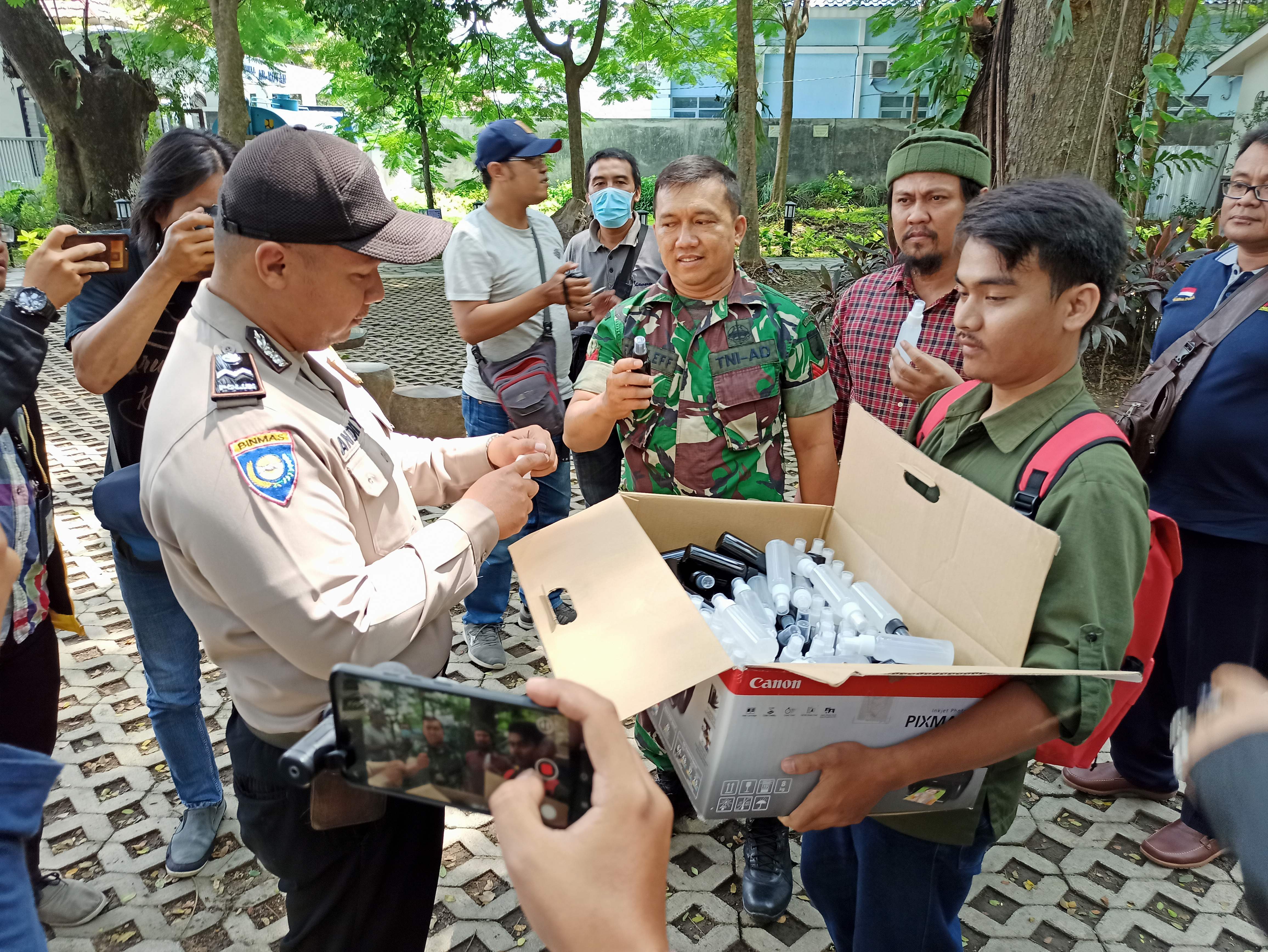 Wartawan peduli corona membagikan hand sanitizer kepada anggota polisi di Kediri. (Foto: Fendhy Plesmana/Ngopibareng.id)