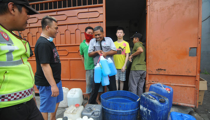 Warga tampak keluar dari toko penjual bahan kimia dengan membawa beberapa jerigen. (Foto: Erfan Hazransyah/Ngopibareng.id)