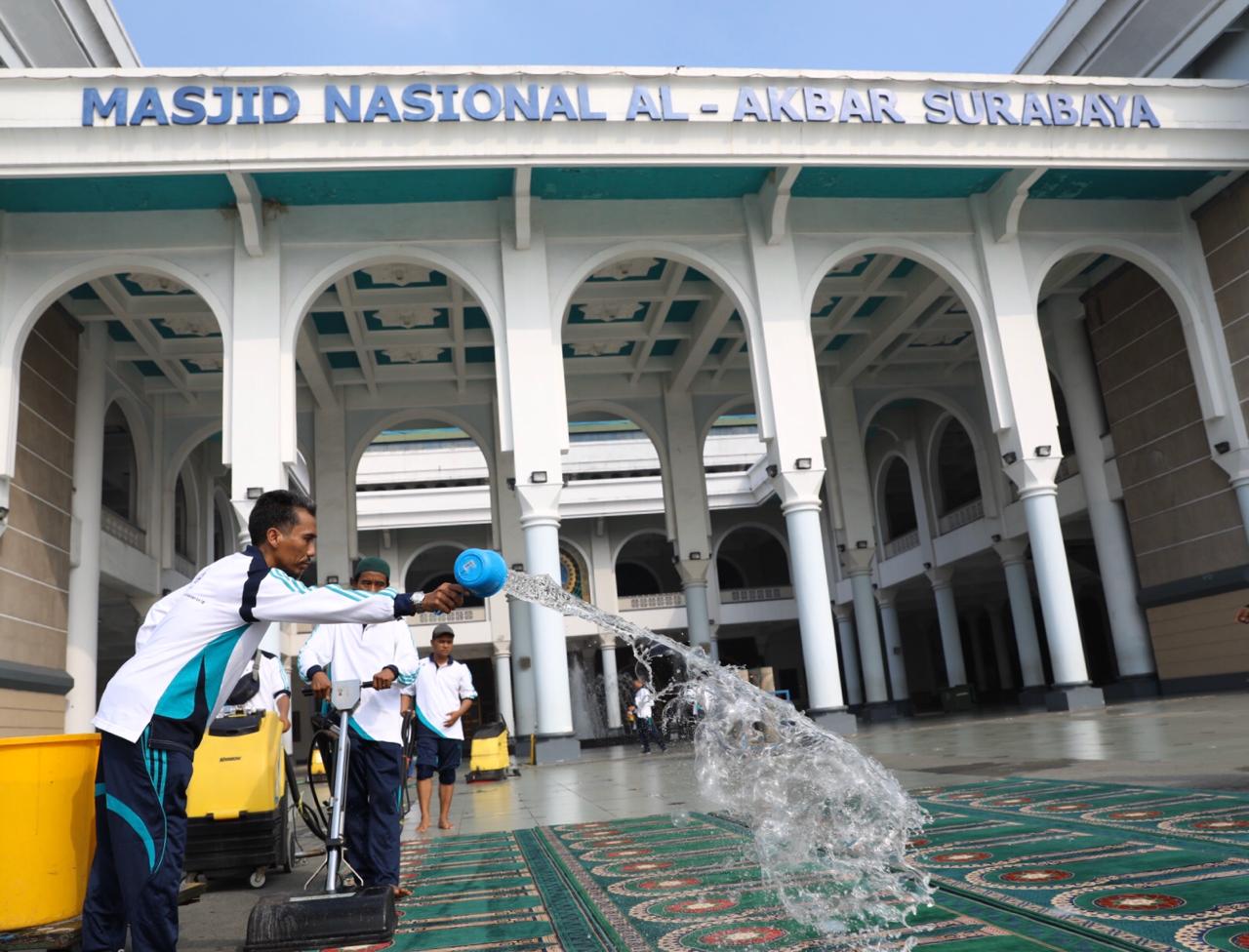 Petugas Masjid Nasional Al Akbar Surabaya, tengah membersihkan sajadah di dalam masjid. (Foto: Andhi Dwi/Ngopibareng.id)