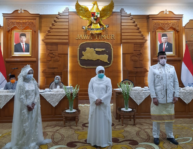 Gubernur Jawa Timur Khofifah Indar Parawansa berdiri di antara dua pasangan pengantin yang resepi di Grahadi. (Foto: Alief Sambogo/Ngopibareng.id)