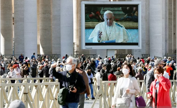  Warga dengan masker pelindung berjalan di St. Peter's Square saat Paus Francis melakukan doa Angelus yang dilakukan setiap minggu melalui video, akibat kekhawatiran virus korona baru, di Vatikan, Minggu 8 Maret 2020. (Foto: Antara/Reuters/Remo Casilli)
