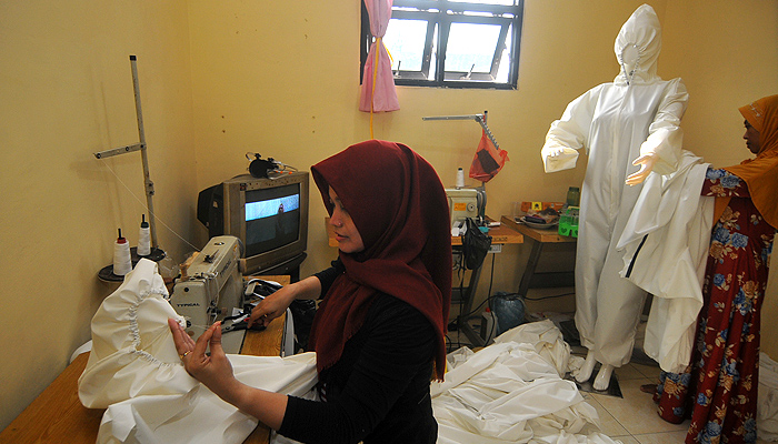 Novita Rahayu Purwaningsih, Pemilik UMKM V-ra Collection (kiri) dibantu karyawannya saat menyelesaikan pembuatan baju Hazmat dirumahnya di jalan Tuwowo Gg 1, Kecamatan Tambaksari, Surabaya. (Foto: Erfan Hazransyah/Ngopibareng.id)