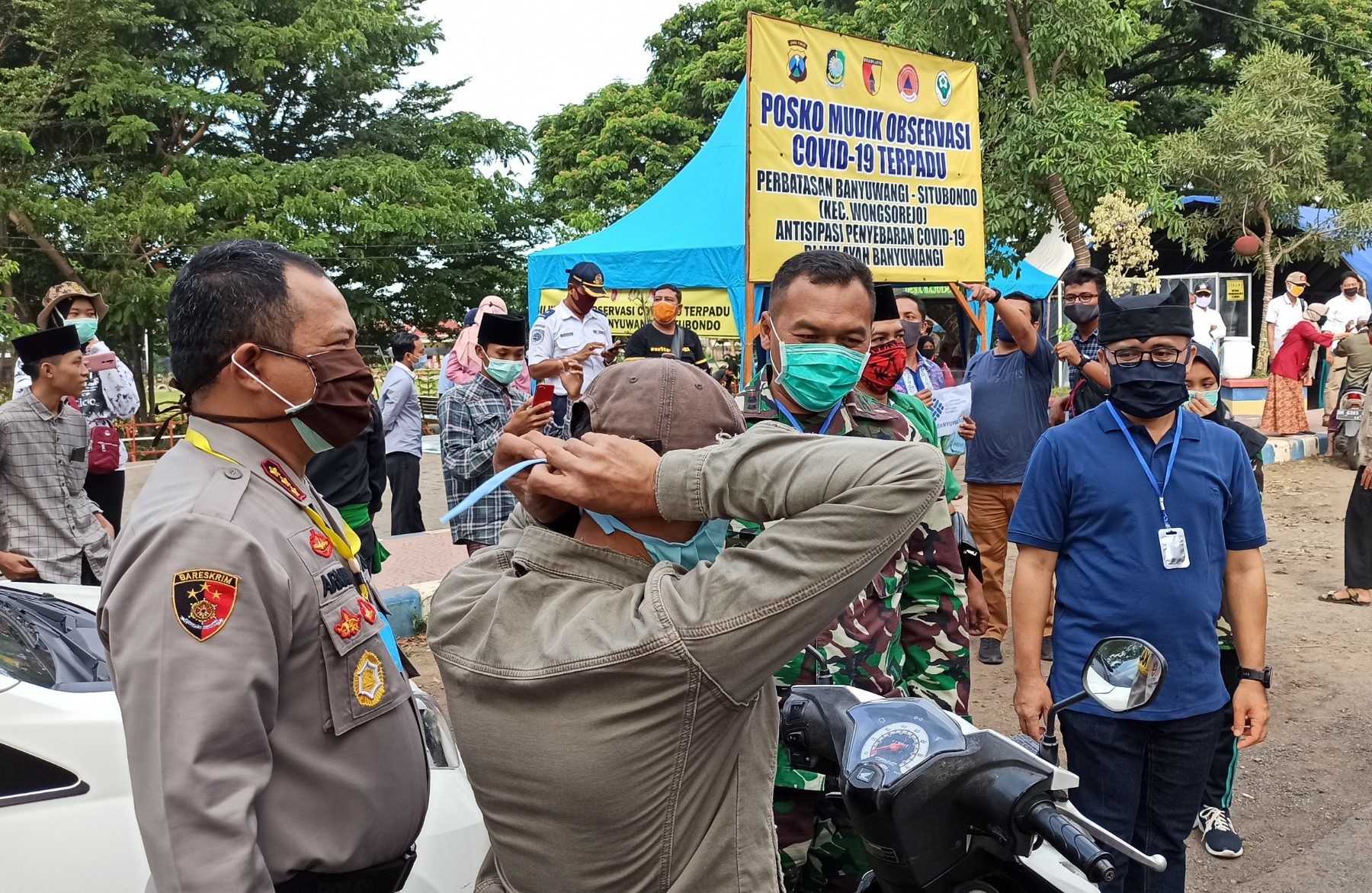 Pimpinan Gugus Tugas Percepatan Penanganan Covid-19 memberikan masker gratis pada masyarakat di Posko screening perbatasan Wongsorejo (foto: Hujaini/ngopibareng.id)
